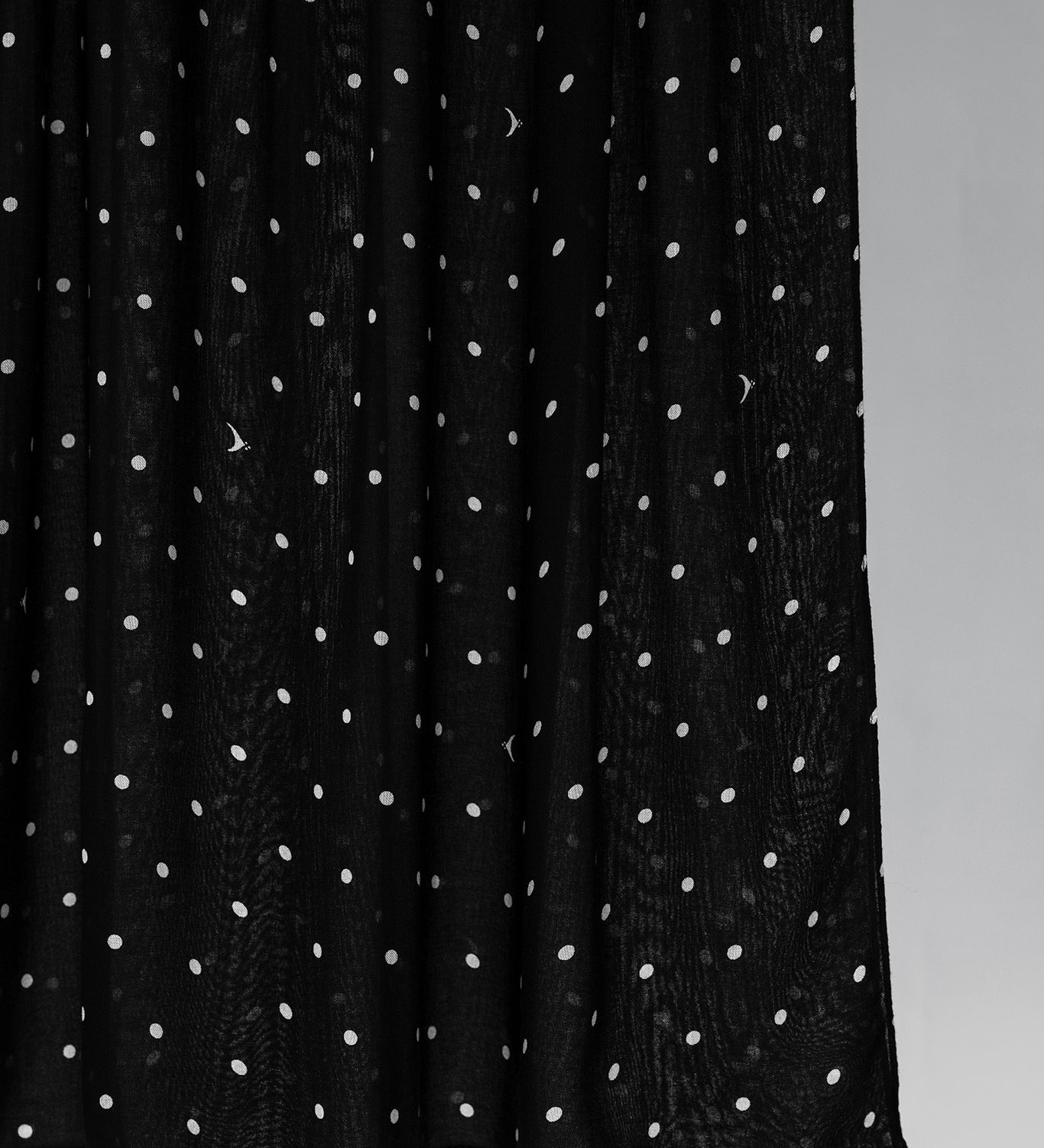 Black hijab fabric with white polka dots on a gray background