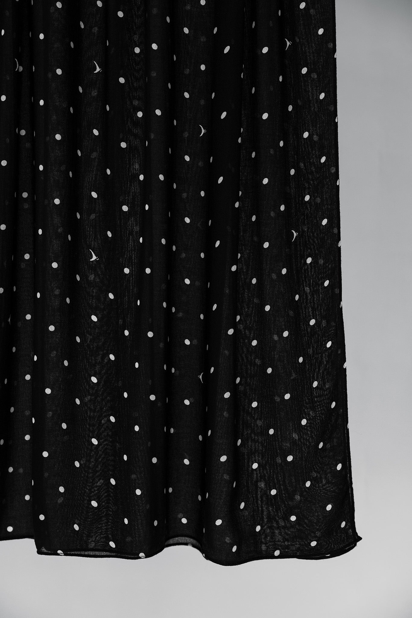 Black hijab fabric with white polka dots on a gray background