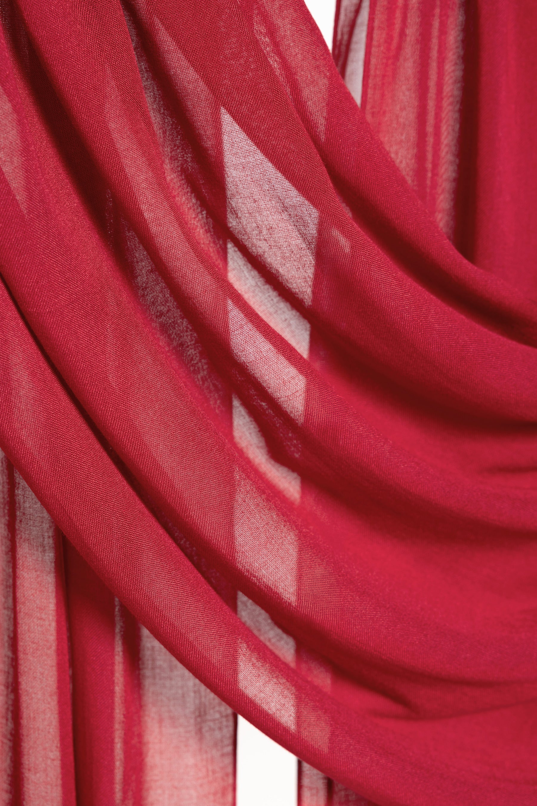 A close-up of draped red sheer fabric with soft folds and translucent texture.