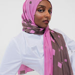 Woman wearing a pink and brown patterned hijab against a white background