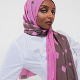 Woman wearing a pink and brown patterned hijab against a white background