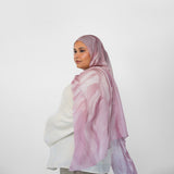 Woman wearing a pink and white patterned hijab on a white background