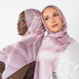 Two women wearing pink sediment hijabs with swirl print against a white background