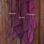 Color comparison of three purple red hijab fabrics labeled 'Rosewood', 'Wild Berry', and 'Fig Latte' on a wooden background.