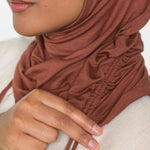 Woman wearing a canyon brown ruching hijab with a taupe top