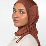 Woman wearing a canyon brown ruching hijab with a taupe top 