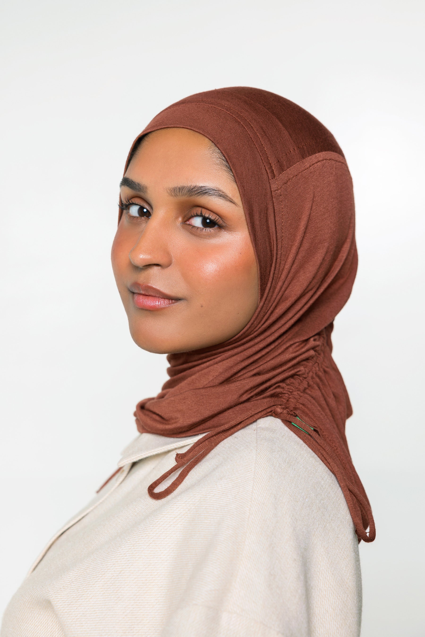 Woman wearing a canyon brown ruching hijab with a taupe top 