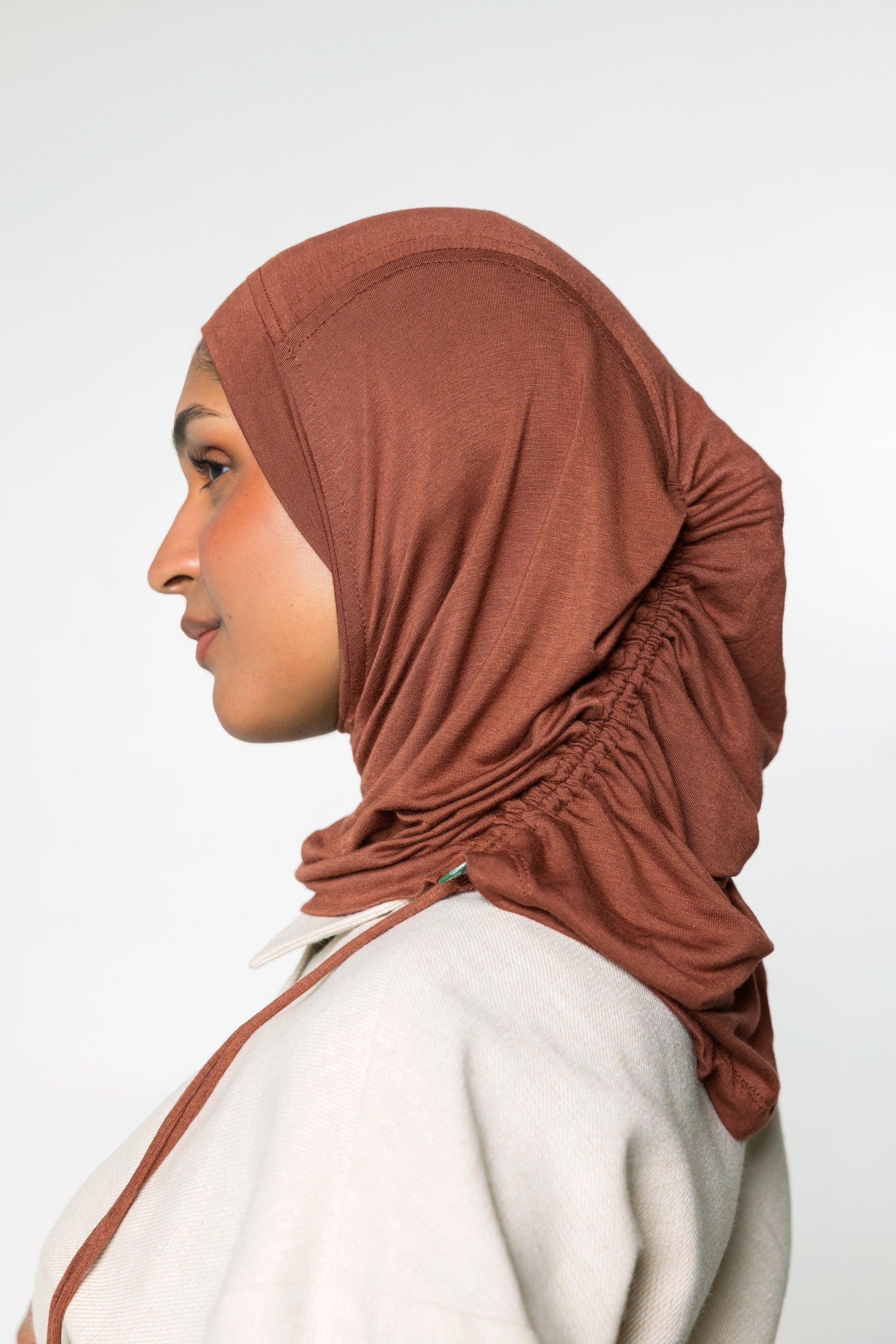 Woman wearing a canyon brown ruching hijab with a taupe top