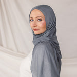 Soft woven hijab in dark sage green, neatly styled on model display its color and lightweight woven texture.
