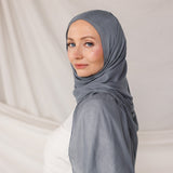 Soft woven hijab in dark sage green, neatly styled on model display its color and lightweight woven texture.