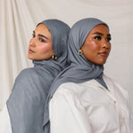 Head-and-shoulders of two models side by side, each wearing the dark sage hijab with one in front and the other in slight profile.
