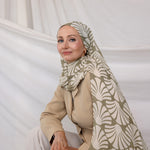 Woman wearing a patterned Sand Shells hijab and beige outfit against a white background