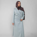 Woman wearing a silver ruched abaya with a white background