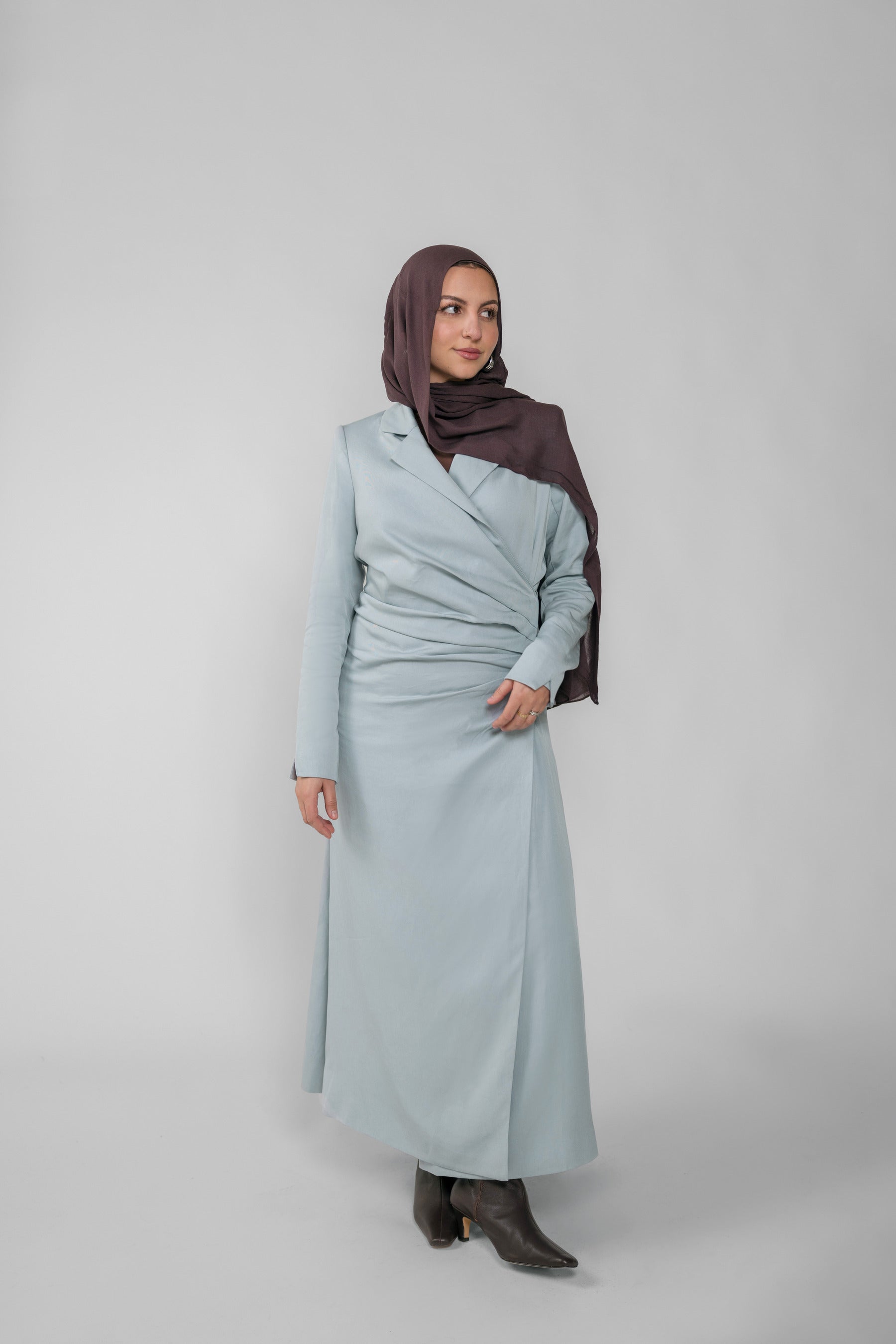Woman wearing a silver ruched abaya with a white background