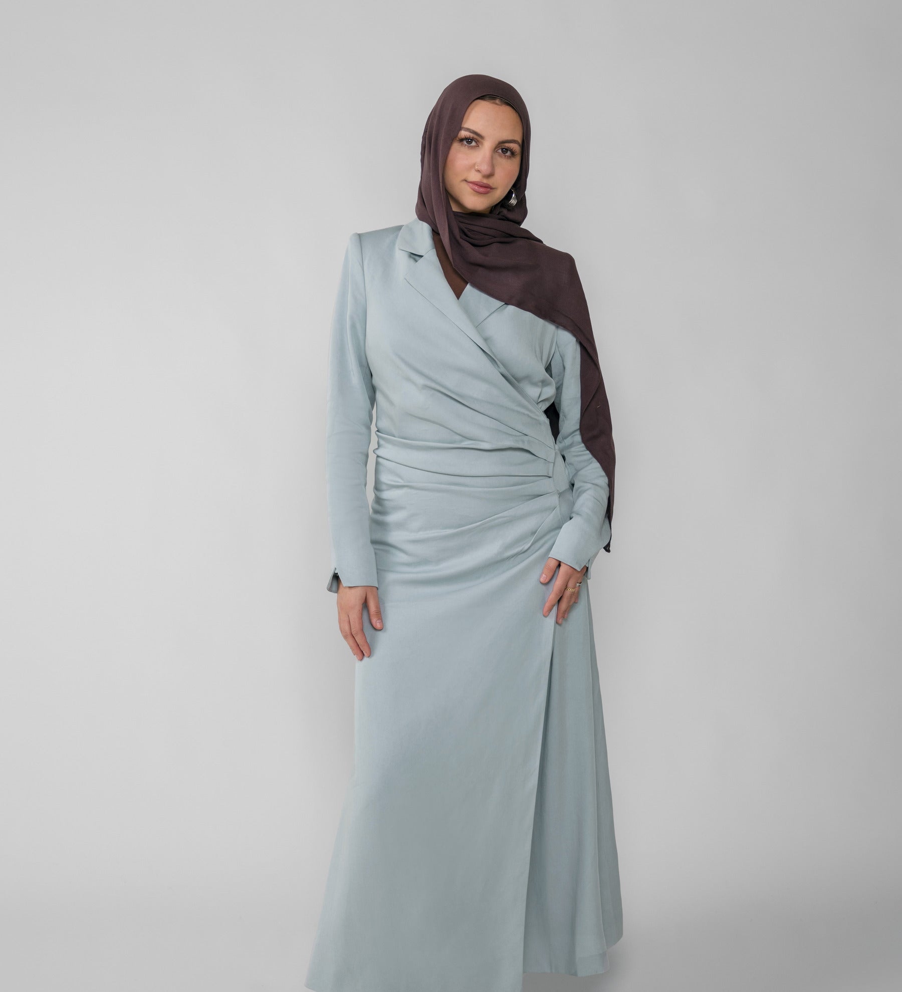 Woman wearing a silver ruched abaya with a white background