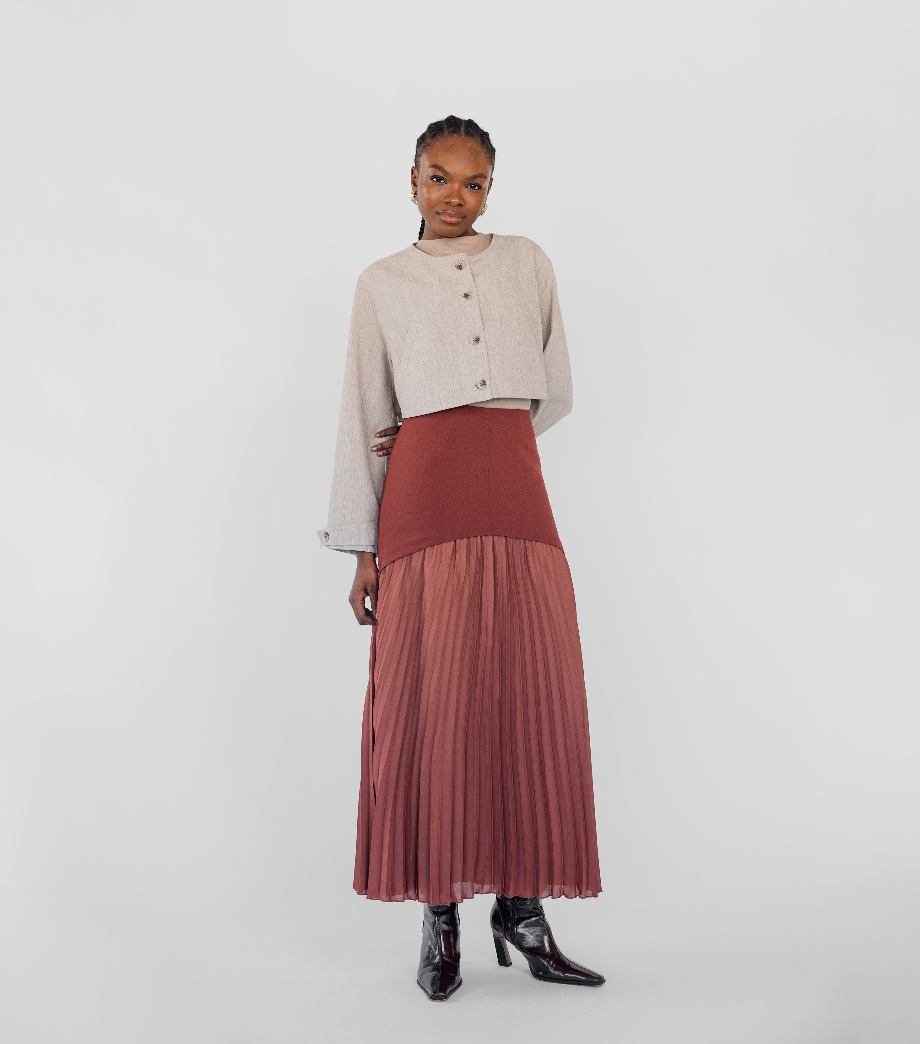 Woman wearing a beige top and red pleated skirt on a white background
