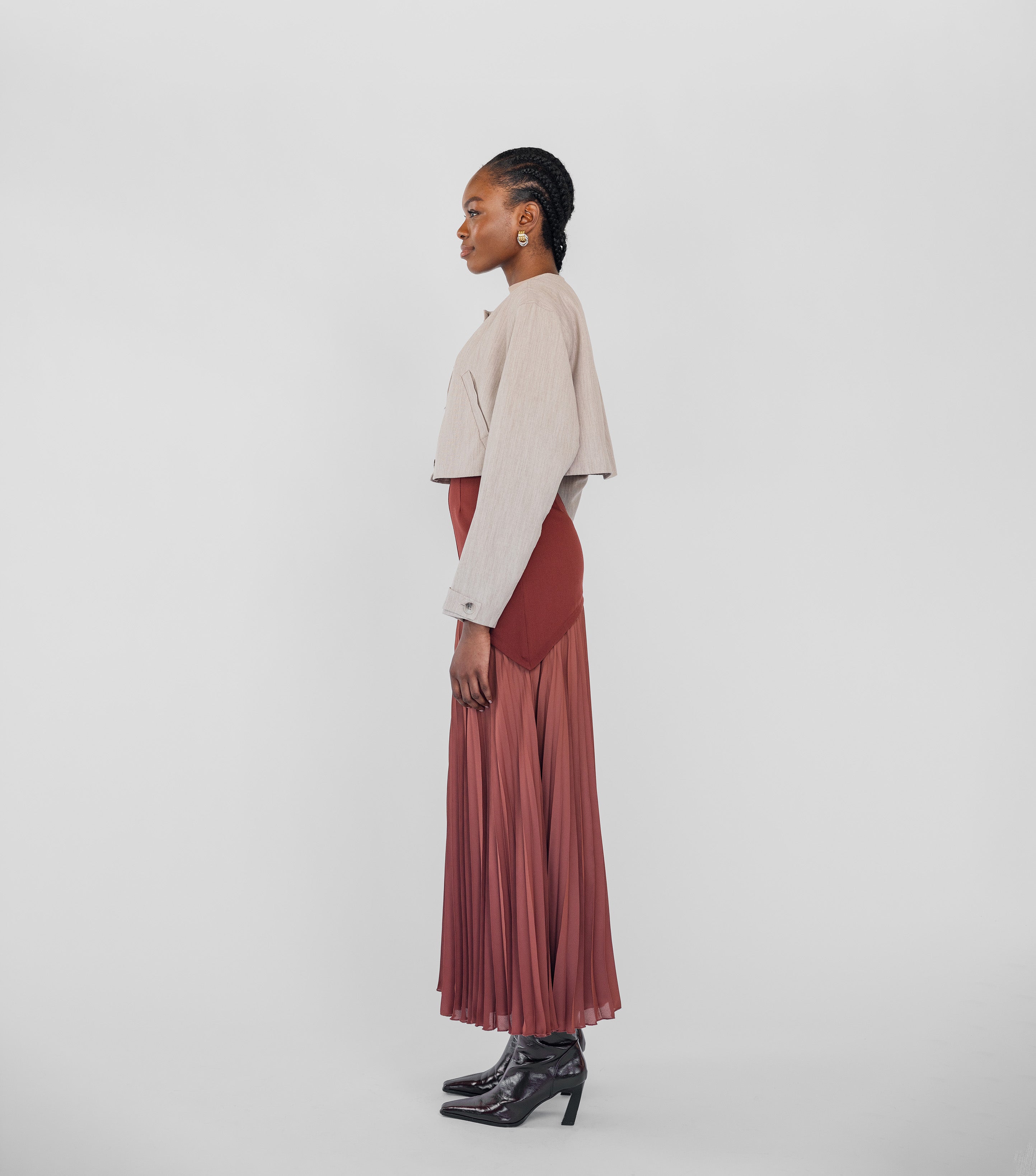 Woman wearing a beige top and red pleated skirt on a white background