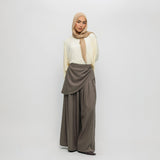 Woman wearing a beige hijab, white top, and brown pants on a white background