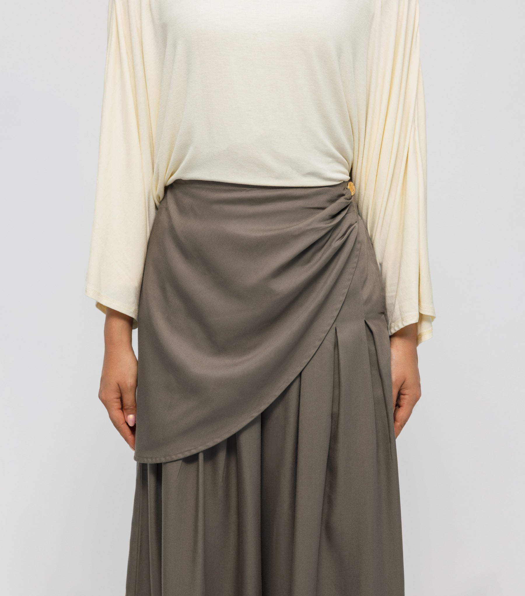 Person wearing a beige top and brown skirt on a plain background