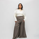 Woman wearing a white blouse and brown skirt against a white background