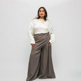 Woman wearing a white blouse and brown skirt against a white background