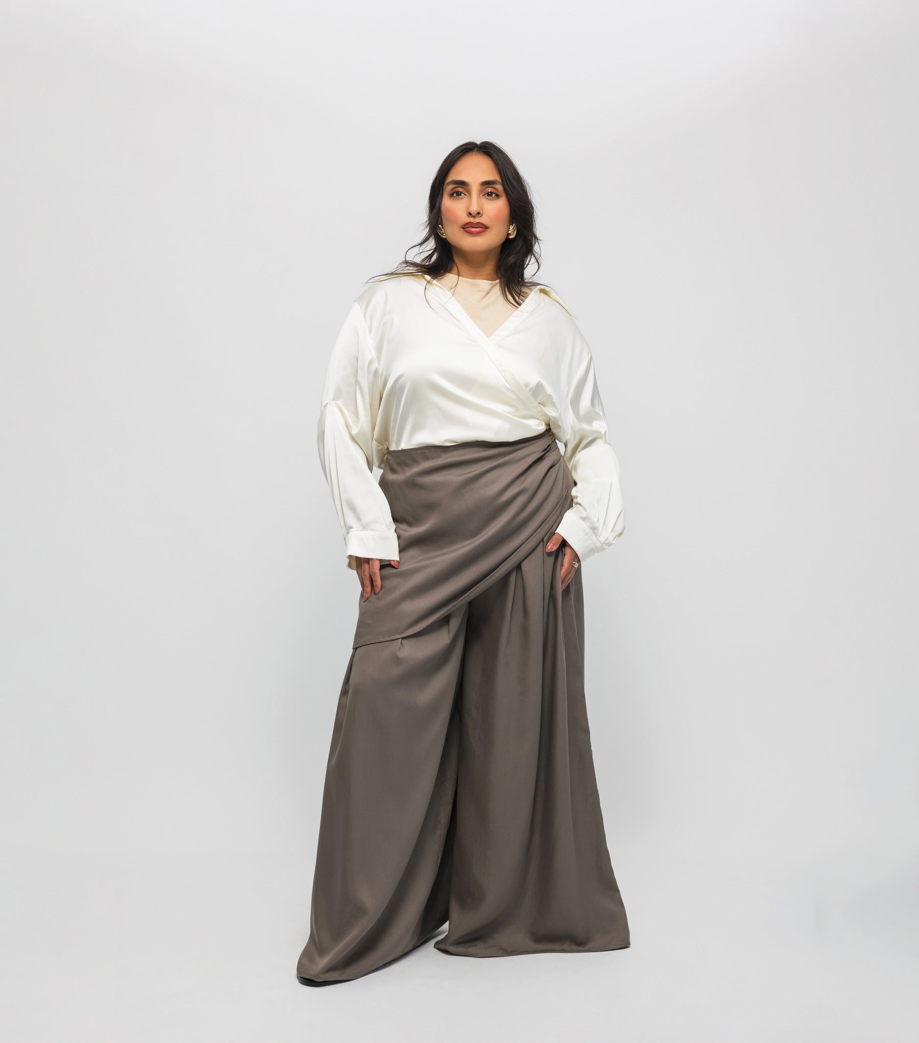 Woman wearing a white blouse and brown skirt against a white background