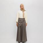 Woman wearing a beige hijab, white blouse, and brown skirt on a white background