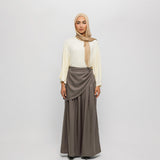Woman wearing a beige hijab, white blouse, and brown skirt on a white background