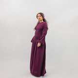 Woman wearing a long burgundy smocked dress on a white background