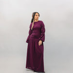 Woman wearing a long burgundy dress against a plain background