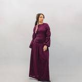 Woman wearing a long burgundy dress against a plain background