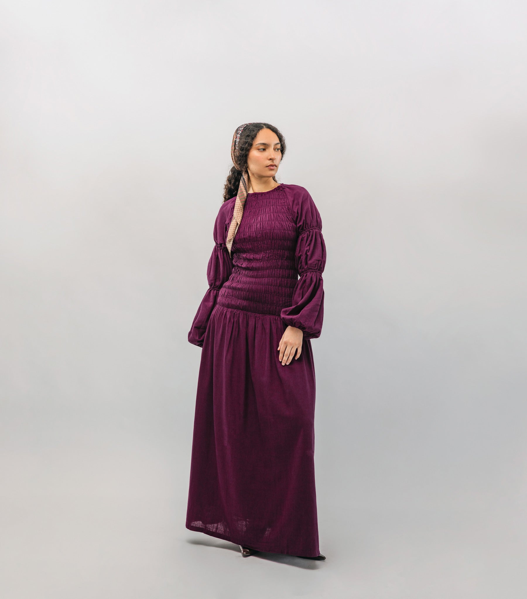 Woman wearing a long burgundy dress against a plain background