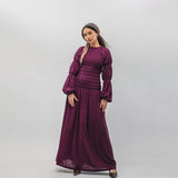Woman wearing a long burgundy dress against a plain background