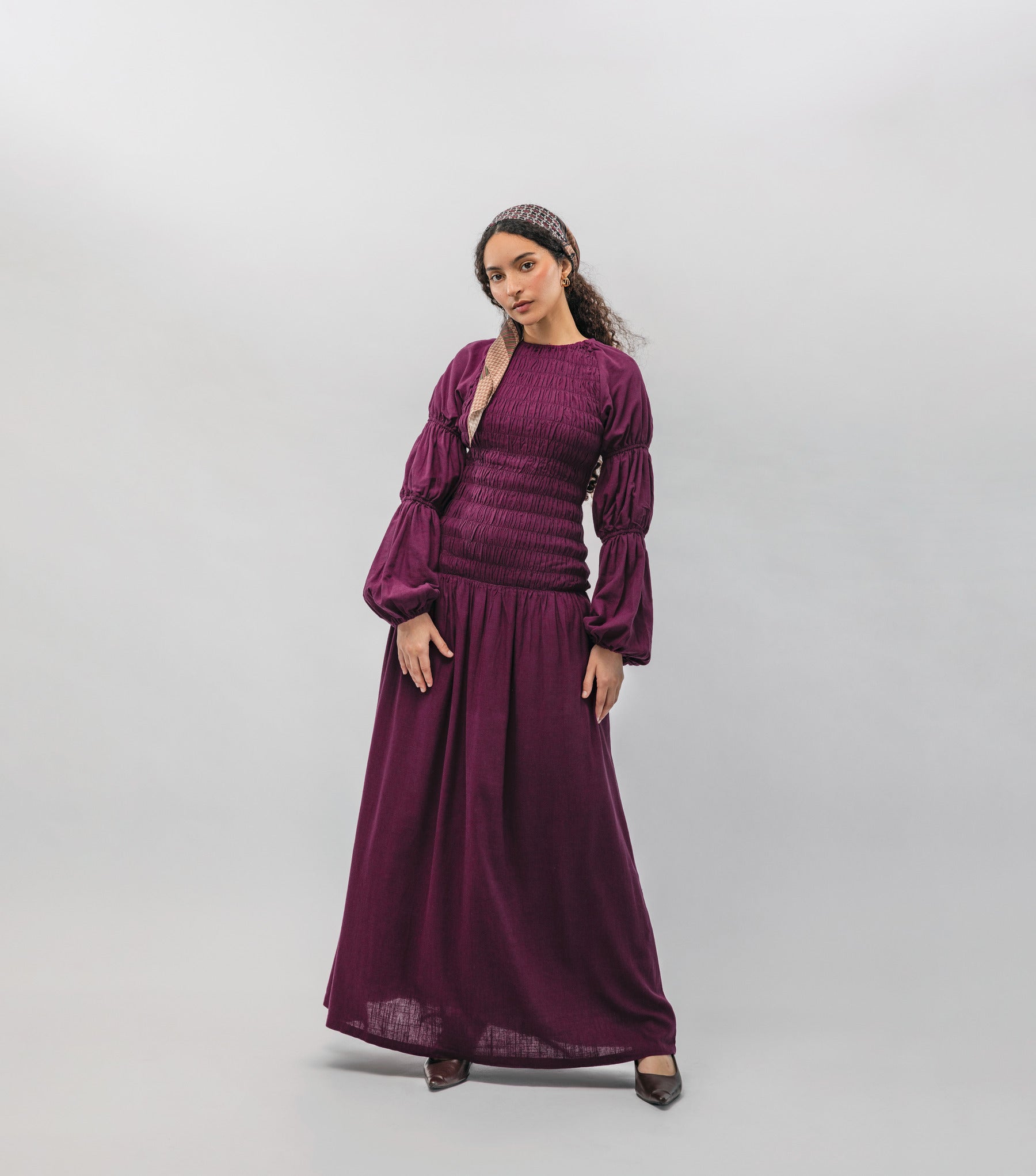 Woman wearing a long burgundy dress against a plain background