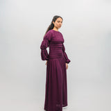 Woman wearing a long burgundy dress against a white background