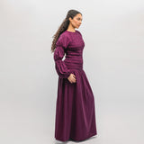 Woman wearing a long burgundy dress against a white background