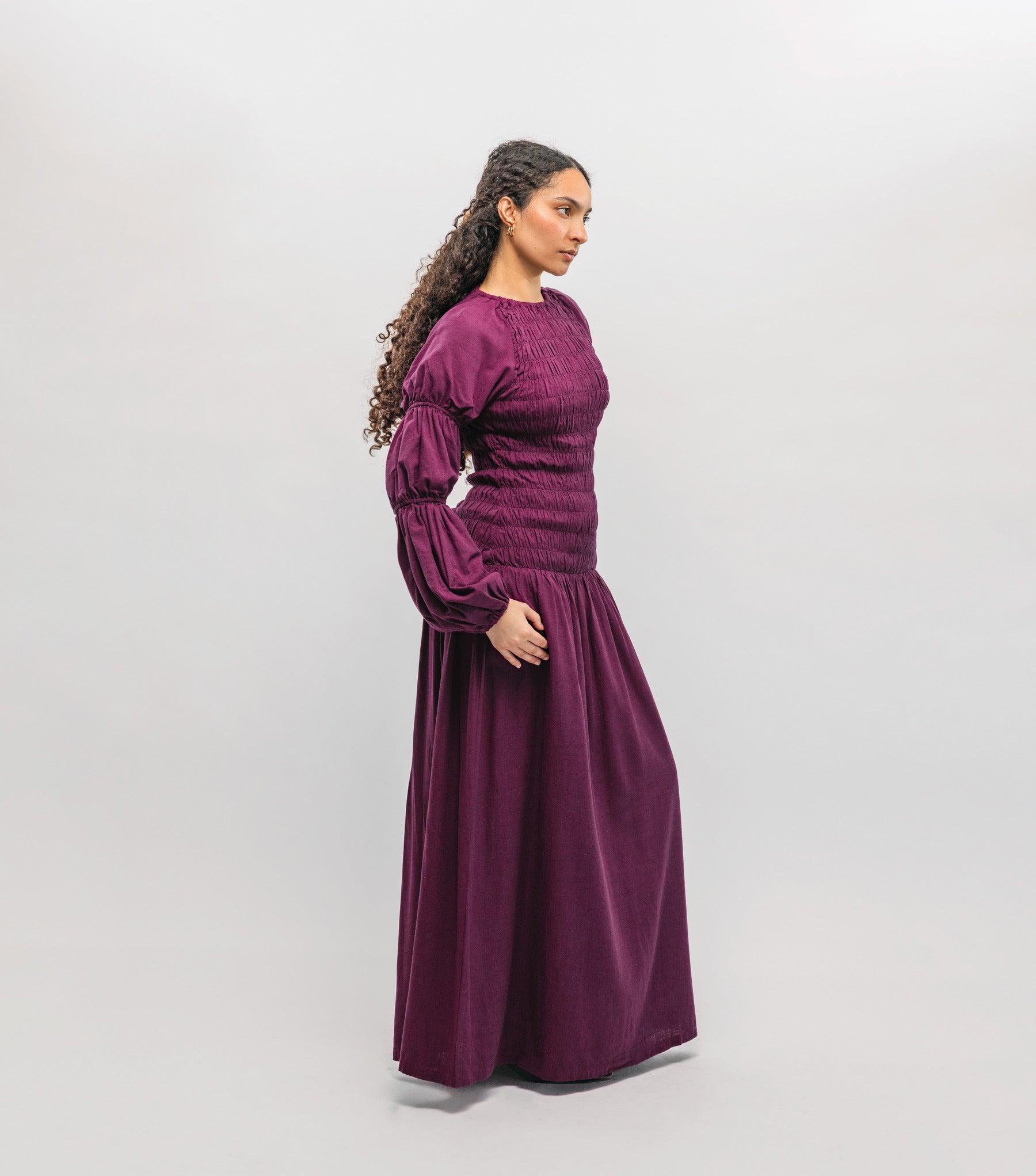 Woman wearing a long burgundy dress against a white background