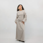 Woman wearing a beige smocked dress against a white background