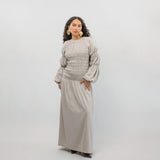 Woman wearing a beige smocked dress against a white background