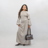 Woman wearing a gray smocked dress with a  handbag on a white background