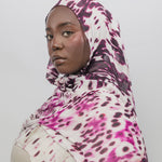 Woman wearing a abstract patterned hijab against a plain background