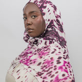 Woman wearing a abstract patterned hijab against a plain background