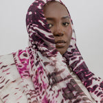 Woman wearing a patterned headscarf against a plain background