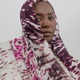 Woman wearing a patterned headscarf against a plain background