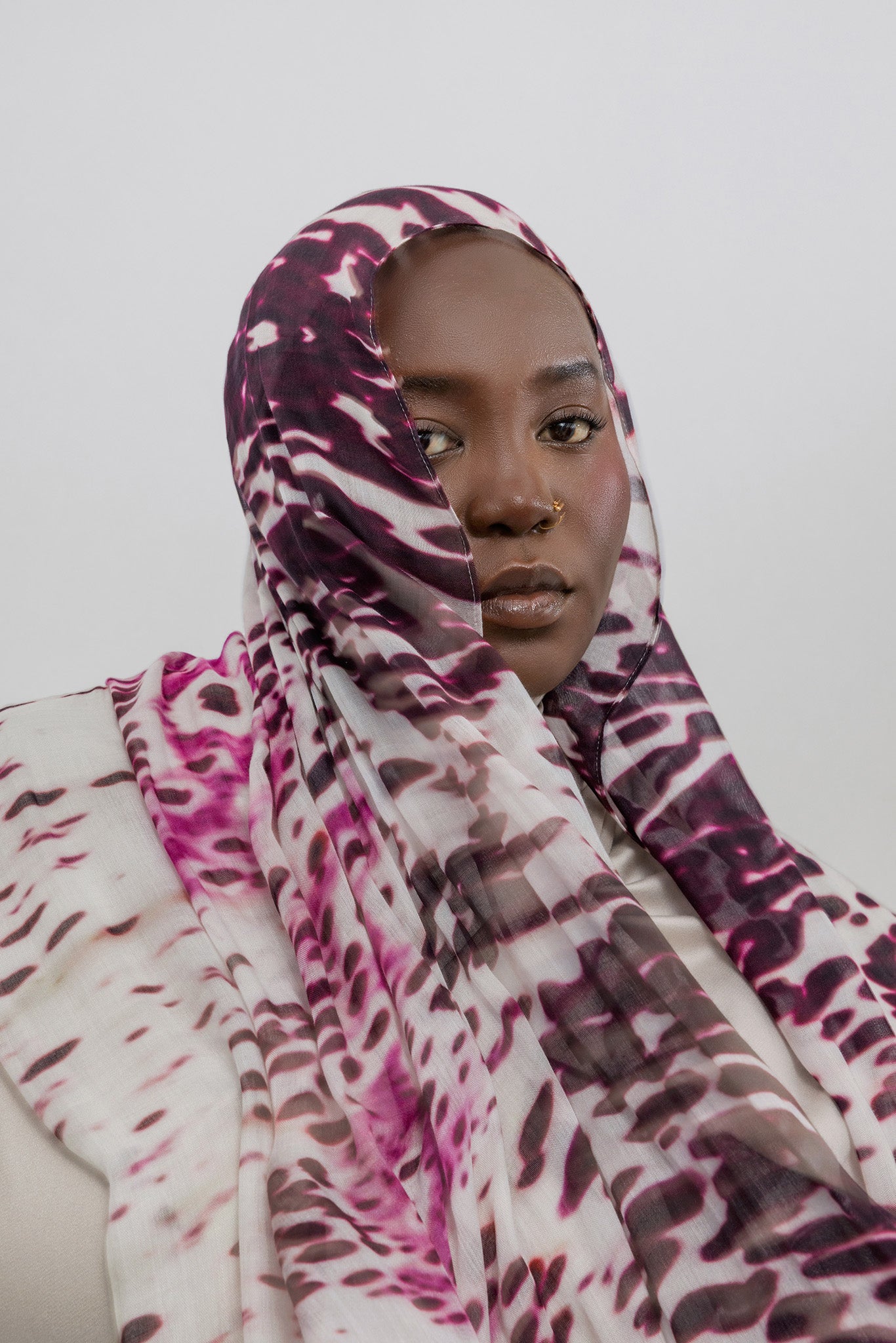 Woman wearing a patterned headscarf against a plain background