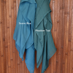 Color comparison of two teal toned hijabs labeled 'Storm Blue' and 'Meadow Teal' on a wooden background.