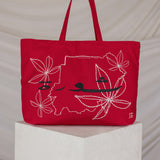 Red tote bag with a map embroidered design on a white pedestal against a beige background