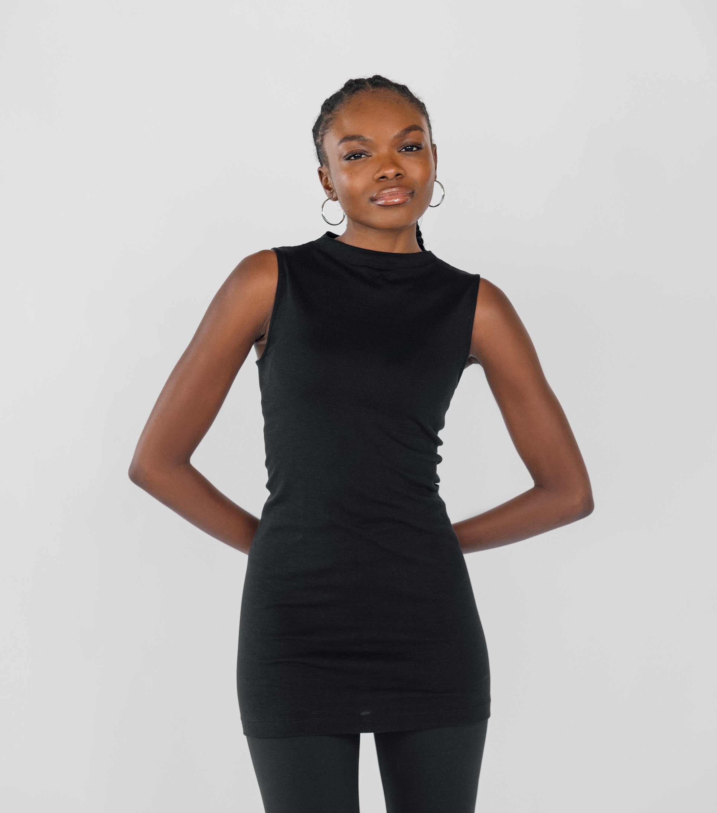 Person wearing a black sleeveless top and black leggings on a white background