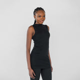 Woman wearing a black sleeveless top and leggings against a white background