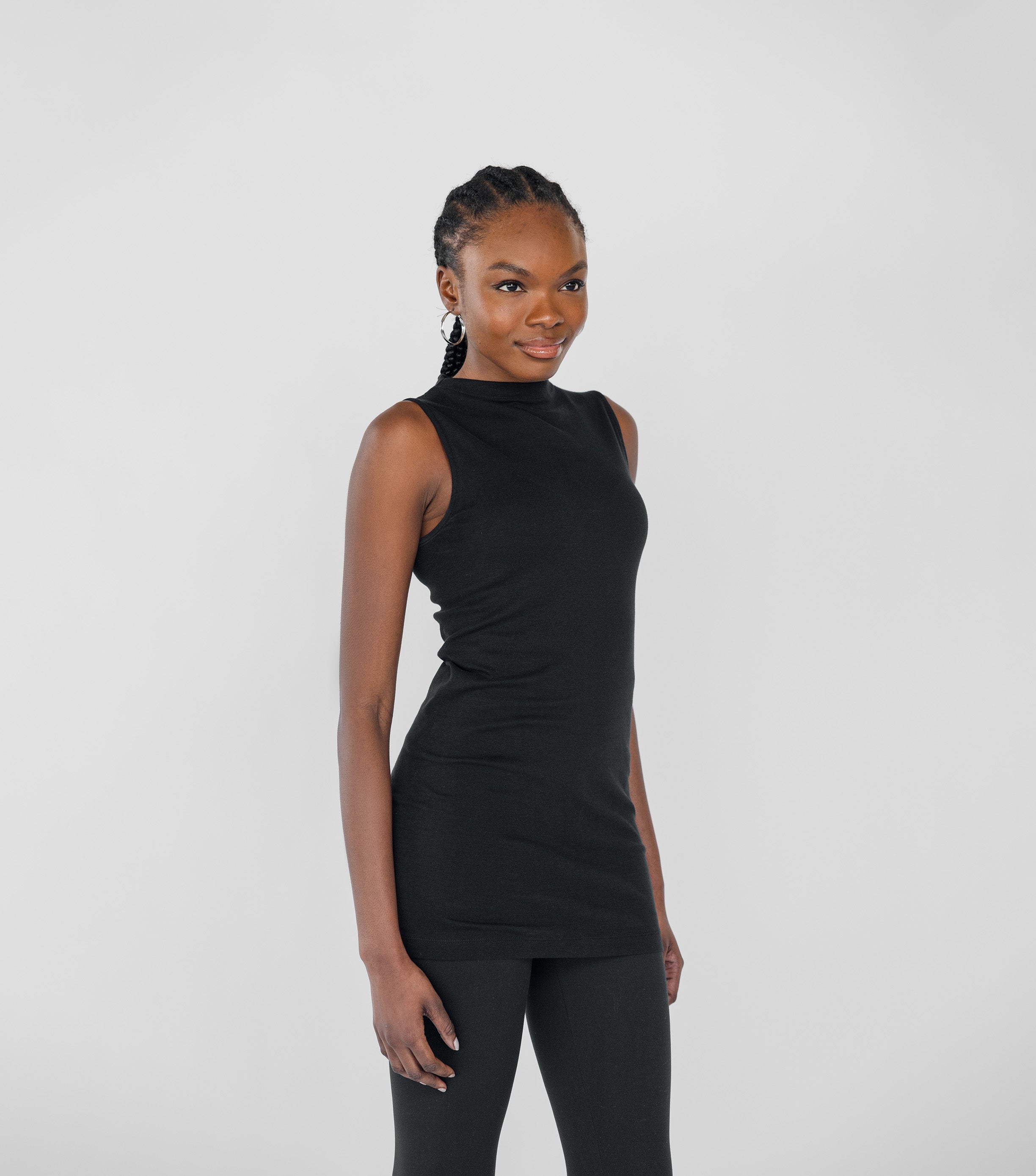 Woman wearing a black sleeveless top and leggings against a white background
